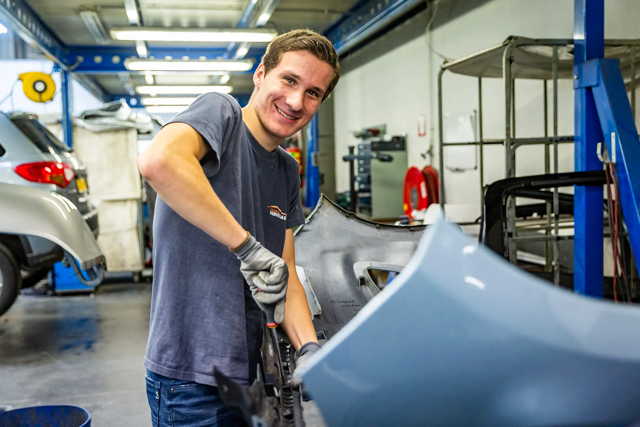 Plaatwerker repareert blikschade aan een bumper in de werkplaats
